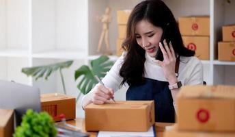 nystartad småföretagare sme frilansande kvinna som arbetar med låda ung asiatisk småföretagare kontor onlinemarknad packbox leverans sm leverans e-handel telemarketing säljare koncept foto