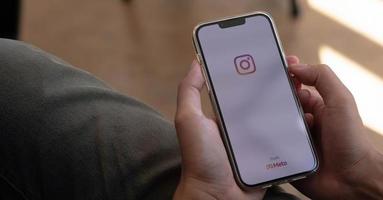 en man håller i apple iphone 13 pro med instagramapplikation på skärmen på café. instagram är en app för fotodelning för smartphones. foto