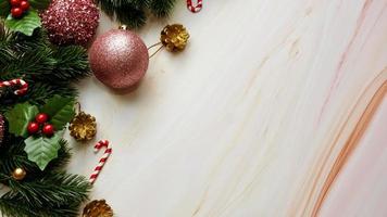 gröna tallblad, rosa juldekorationer och godisrör på mjuk marmorbakgrund, juldekorationer i ljusa och snygga rosa färger. enkelt och kreativt julkoncept. foto