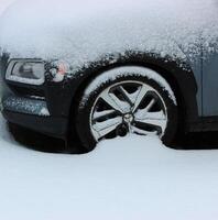 främre bil hjul täckt med snö detaljerad bild foto