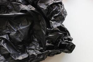 krossad vadad upp ark av svart polyeten på vit bakgrund. stock Foto för plast återvinning