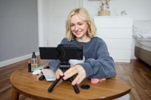 porträtt av ung Tonårs flicka i henne rum, inspelning en vlogg, dagligen livsstil för social media, internet influencer reklam produkt uppkopplad, talande till de kamera, Sammanträde på de golv foto