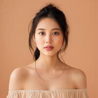 porträtt av skön ung asiatisk kvinna ser på kamera, skönhet färsk hud isolerat på orange bakgrund foto