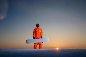 snowboardåkare på toppen av skidbacken i bakgrunden av vacker solnedgång foto