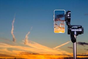 använda smartphone på stativ för att fånga fantastisk solnedgång foto