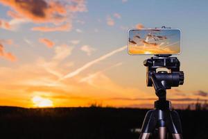 smartphone på stativ som tar en bild av fantastisk solnedgång foto