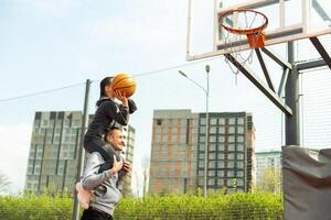 Lycklig far och tonåring dotter utanför på basketboll domstol. foto