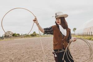 Söt kinesisk cowgirl kasta de lasso i en häst hage foto