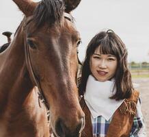 söt kinesisk cowgirl medan tar vård av henne häst foto