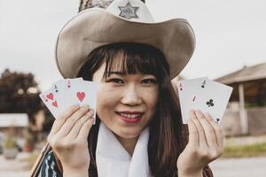 porträtt av en skön kinesisk kvinna cowgirl spelar med poker kort foto