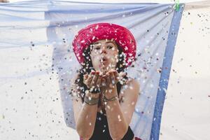 Söt kvinna med färgrik sugrör hatt blåser konfetti foto