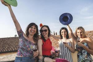 grupp av kvinna vänner har roligt medan dricka röd vin på de tak foto