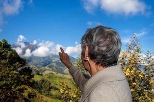 senior kvinna turist ser på de Fantastisk landskap av de central intervall på de uppstigning till de hög av brev mellan de städer av fresno och manizales i colombia foto