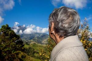 senior kvinna turist ser på de Fantastisk landskap av de central intervall på de uppstigning till de hög av brev mellan de städer av fresno och manizales i colombia foto