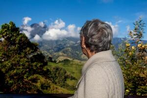 senior kvinna turist ser på de Fantastisk landskap av de central intervall på de uppstigning till de hög av brev mellan de städer av fresno och manizales i colombia foto