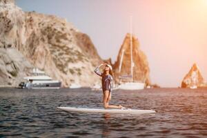 kvinna supera yoga. mitten ålder sportig kvinna praktiserande yoga pilates på paddla supera surfbräda. kvinna stretching håller på med träna på hav vatten. modern enskild kvinna hipster utomhus- sommar sport aktivitet. foto