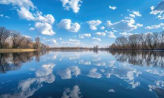 en lugn vår sjö reflekterande de klar blå himmel och fluffig vit moln foto