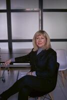porträtt av en blond mitten ålder kvinna i en företag kostym i de kontor foto