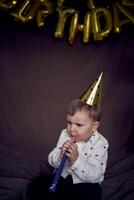 en litet barn i en fest keps slag en vissla flöjt foto