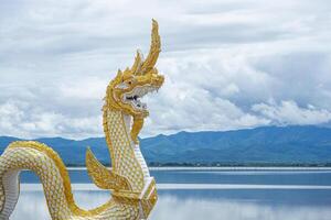 naga staty eller phayanak med en ljus himmel, moln, bergen bakgrund och sötvatten sjö i phayao, thailand foto