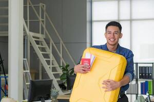 ung man leende och innehav stor gul bagage förbereda för de kommande Semester. Semester begrepp foto