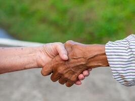 närbild bild av skakning händer mellan senior kvinnor. enhet och partnerskap begrepp foto