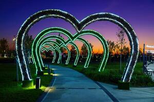dekorationer i de form av valv i de form av hjärtan från led belysning över de trottoar i de natt stad parkera. foto