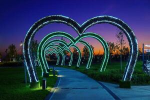 dekorationer i de form av valv i de form av hjärtan från led belysning över de trottoar i de natt stad parkera. foto