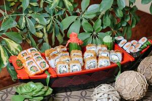 bricka av sushi på tabell Nästa till inlagd växt foto