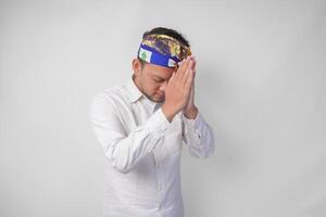 balinesisk man bär traditionell huvudbonad kallad udeng håller på med bön- hand eller betalande respekt gest på isolerat vit bakgrund foto