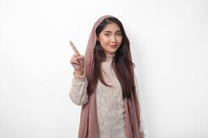 porträtt av attraktiv asiatisk muslim kvinna bär slöja hijab ger siffra ett till tio förbi hand gest, stående över isolerat vit bakgrund foto