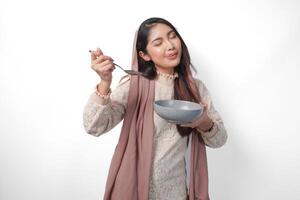 porträtt av en hungrig asiatisk muslim kvinna innehav bestick till äta eller smak utsökt maträtter på de kopia Plats över de tallrik, isolerat vit bakgrund foto