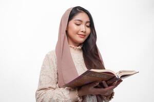 allvarlig asiatisk muslim kvinna bär slöja hijab bön- och läsning al Koranen, stående över isolerat vit bakgrund. ramadan och eid mubarak begrepp foto