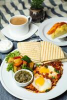 Shakshuka med vegetabiliska sallad inkludera tomat, potatis, sallad blad och morot med te, kaffe, och ljuv melon eras på mat tabell topp se friska frukost foto