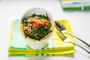 tabouleh sallad, tabouli med tomat och hackad grön löv eras i maträtt isolerat på tabell topp se av arabicum mat foto