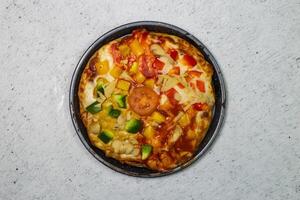 vegetabiliska pizza garnering med tomat, lök, gurka, svamp och ost eras i maträtt isolerat på grå bakgrund topp se av bangladeshiska snabbmat foto