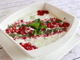 mast o khiar eller persisk yoghurt dopp med mynta lämna och granatäpple frön raita eras i maträtt isolerat på trä- tabell topp se av kall mazza arabicum mat foto