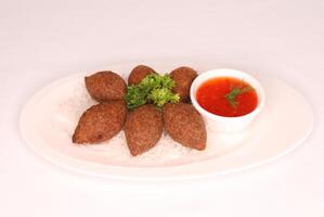 kött kibbeh med chili sås eras i maträtt isolerat på bakgrund sida se av arab mat foto