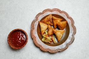 Krispig samosa fylld med kyckling och grönsaker med chili sås tomat ketchup eras i maträtt isolerat på tabell topp se av indian, bangladeshiska och pakistansk gata mat foto