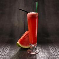 vattenmelon juice med sugrör eras i glas isolerat på tabell sida se friska morgon- dryck foto