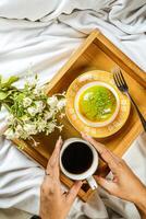 citron- pistasch munk med kopp av kaffe, gaffel och blommor eras i tallrik isolerat på trä- bricka topp se av bakad frukost mat foto