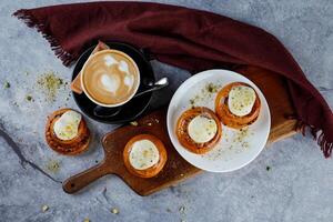kanel rulla eras på trä- styrelse med kopp av kaffe latte konst isolerat på servett topp se av franska frukost bakad mat Artikel foto
