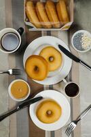 enkel munkar med dopp och kopp av kaffe isolerat på servett topp se av bakad mat frukost på tabell foto