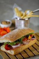 ciabatta rökt skinka smörgås isolerat på trä- med majonnäs dopp och franska frites hink styrelse sida se av italiensk snabb mat på grå bakgrund foto