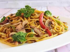 kyckling teriyaki spaghetti inkludera broccoli, morot, tomat och vår lök eras i maträtt isolerat på tabell närbild sida se av kinesisk mat foto