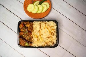 achari kyckling pulao biryani ris med gurka och citron- skiva eras i maträtt isolerat på trä- tabell topp se närbild av bangladeshiska och indisk kryddad lunch mat foto