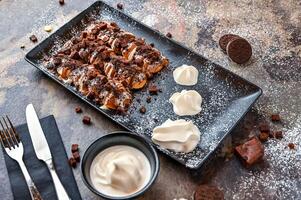 oreo och tomte puffar med choklad, vispad grädde, kniv och gaffel eras i maträtt isolerat på mörk bakgrund närbild topp se av Kafé bakad efterrätt mat foto