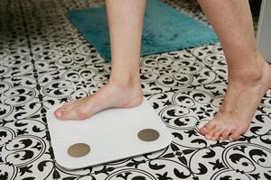 kvinna kontroll henne vikt på vägning skalor i badrum foto