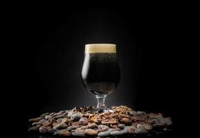 mörk svart stout öl pint över en hög med kakaonibs och bönor foto