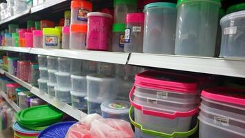 tallrikar, skedar, plast hinkar, skålar, mat lagring behållare och kök redskap på mataffär hyllor, för försäljning foto